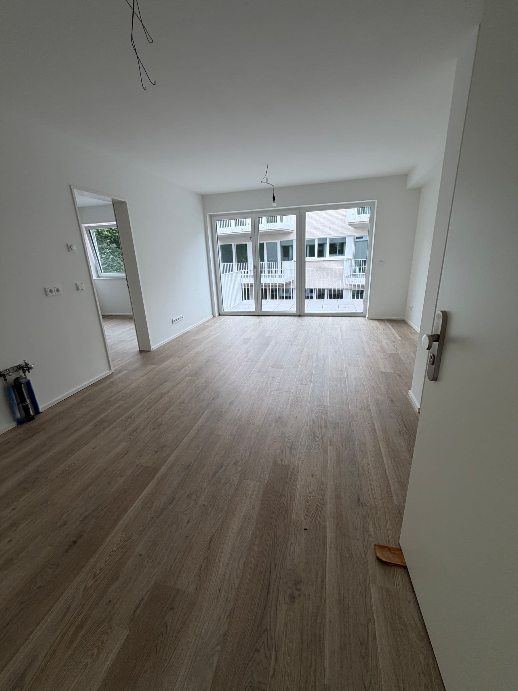 Heller Wohnbereich mit Fensterfront und Blick in den Hof